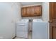 A dedicated laundry room with overhead cabinets and side by side washer and dryer at 7856 Trotwood Cir, Indianapolis, IN 46256