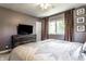 Comfortable bedroom features a ceiling fan, dresser with TV, and a window with natural light at 845 W 77Th St S Dr, Indianapolis, IN 46260