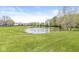 Peaceful pond surrounded by lush green grass and mature trees, creating a serene setting at 9037 Carnation Dr, Noblesville, IN 46060