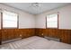 Bedroom with wood paneled walls, neutral carpet, two windows, and ceiling fan at 9303 Leroy Rd, Brownsburg, IN 46112