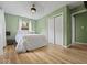 Comfortable bedroom featuring green walls, hardwood floors, a ceiling fan, and a spacious closet at 961 N Dellasburg Rd, Columbus, IN 47203
