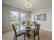 Dining room with glass table, four chairs, elegant lighting and backyard views at 10599 Geist View Dr, Fishers, IN 46055