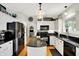 Updated kitchen with white cabinets, black appliances, granite countertops, and hardwood floors at 10764 Gettysburg Pl, Carmel, IN 46032