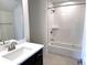 Clean bathroom design with a dark vanity, white tub, and matching subway tile at 14913 Higgins Dr, Westfield, IN 46074