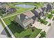 Aerial view of a green two-story home with a well-manicured lawn and view of neighborhood pond and fountain at 16112 Lavina Ln, Fishers, IN 46040