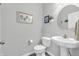 Well-lit bathroom with modern fixtures, including a pedestal sink and a decorative round mirror at 2261 Shadow Trace Way, Greenwood, IN 46143