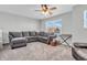 Comfortable living room features a plush gray sectional sofa, a ceiling fan, and a bright window at 2261 Shadow Trace Way, Greenwood, IN 46143