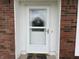 Close-up of the front door with a storm door, surrounded by brick and white trim at 247 N 150 W, Greenfield, IN 46140