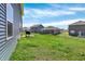 View of the backyard showcasing a well-manicured lawn, patio with grill, and adjacent homes in the neighborhood at 2972 W Patchwork Dr, Monrovia, IN 46157