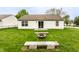 Large backyard with a green lawn, fire pit, two concrete benches, and a sliding glass door at 4303 Cowslip Ct, Indianapolis, IN 46203