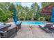 Backyard pool with lounge chairs, umbrella, and mature trees, creating a serene outdoor space at 4401 W Hunters Ridge W Ln, Greenwood, IN 46143