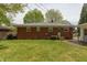 View of the backyard featuring a brick home, green grass, and mature trees at 4468 N Elizabeth St, Indianapolis, IN 46226