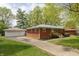 A red brick home with a detached garage featuring a well-kept lawn and a paved driveway at 4468 N Elizabeth St, Indianapolis, IN 46226