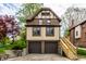 Charming Tudor-style home with a two-car garage, side entrance with wooden stairs, and stone retaining wall at 5124 N Capitol Ave, Indianapolis, IN 46208