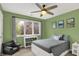 Cozy bedroom with a gray bed, green walls, ceiling fan and view to outside trees at 5255 Apache Moon, Carmel, IN 46033
