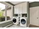 Convenient laundry room with white cabinets, modern washer and dryer, and natural light from a large window at 5255 Apache Moon, Carmel, IN 46033