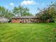 Grassy backyard with brick house and a small wooden deck at 5305 N Cork Dr, Muncie, IN 47304