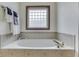 Soaking tub in bathroom featuring tile surround and a glass block window at 5499 Steven Dr, Greenwood, IN 46142