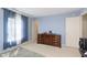 Carpeted bedroom featuring bright window with curtains and a wooden dresser against blue walls at 5646 Skipping Stone Dr, Indianapolis, IN 46237