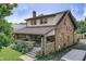 Spacious home showcasing a covered porch, brickwork, and lush landscaping at 6051 Lowell Ave, Indianapolis, IN 46219