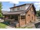 A brick two-story home featuring a covered front porch, mature trees, and a well-maintained lawn at 6051 Lowell Ave, Indianapolis, IN 46219