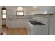 Bright kitchen features white cabinets, stainless sink, gas range and wood flooring at 6051 Lowell Ave, Indianapolis, IN 46219