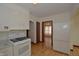 White kitchen features stainless sink, gas range, wood floors and access to other rooms at 6051 Lowell Ave, Indianapolis, IN 46219