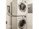 A stacked, front-load washer and dryer set in a modern laundry room with white walls at 622 E 10Th St # 212, Indianapolis, IN 46202