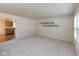 Open-concept living room featuring neutral carpet, modern shelving, and kitchen access at 6516 Amherst Way, Zionsville, IN 46077