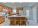 Kitchen with a central island with breakfast bar, wooden cabinets, white appliances, and light tile floors at 710 Monarch Ln, Lebanon, IN 46052