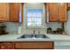 Kitchen sink featuring a large window, wooden cabinets, white countertop and stainless steel double basin sink at 710 Monarch Ln, Lebanon, IN 46052
