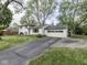 Charming two-story home featuring a brick facade, attached garage, and a driveway surrounded by mature trees at 7216 N Parker Ave, Indianapolis, IN 46240