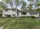 Classic white brick home featuring shuttered windows, a well-manicured lawn, and an attached two car garage at 7216 N Parker Ave, Indianapolis, IN 46240