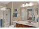 Well-lit bathroom featuring a shower, wood cabinets, a white toilet, and a decorative mirror at 8120 Glenwillow Ln # 206, Indianapolis, IN 46278