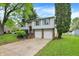 Split-level home showcasing an attached garage, healthy green lawn, and mature trees at 831 Wakulla Ct, Indianapolis, IN 46217