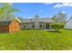 View of home exterior featuring a spacious yard, matching storage shed, and verdant foliage at 8451 Sunningdale Blvd, Indianapolis, IN 46234