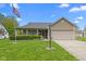Charming single-story home with a well-manicured lawn, covered porch, and two-car garage on a sunny day at 8451 Sunningdale Blvd, Indianapolis, IN 46234