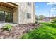 Exterior view of the condo's patio with sliding glass door, lawn, mulch bed and tennis court in the background at 8720 Yardley Ct # 100, Indianapolis, IN 46268