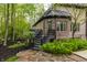 Backyard stairs lead to a deck with black railings surrounded by trees, mulch, and stone walkway at 9312 Sullivan Pl, Zionsville, IN 46077