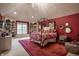 Inviting bedroom features a vaulted ceiling, canopy bed, bright red accent wall, and unique decor throughout at 9312 Sullivan Pl, Zionsville, IN 46077