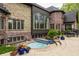 Outdoor hot tub is surrounded by a stone patio and lush landscaping with a partial view of the estate home at 9312 Sullivan Pl, Zionsville, IN 46077