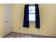 A bright bedroom featuring a window with dark-blue curtains and neutral-colored walls at 1020 E Sixth St, Greenfield, IN 46140
