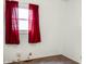 A bedroom with neutral walls and carpet, with a window featuring red curtains at 1020 E Sixth St, Greenfield, IN 46140