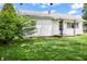 Quaint single-story home with white siding, a covered porch and lush green lawn surrounded by mature landscaping at 1020 E Sixth St, Greenfield, IN 46140