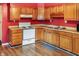 Functional kitchen with oak cabinets, laminate countertops, and modern appliances set against vibrant red walls at 1020 E Sixth St, Greenfield, IN 46140