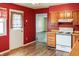 Bright kitchen with red walls, light wood cabinets, and an adjoining dining area with hardwood floors at 1020 E Sixth St, Greenfield, IN 46140