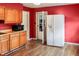 Cozy kitchen featuring bright red walls, oak cabinets, modern appliances, and access to the backyard at 1020 E Sixth St, Greenfield, IN 46140