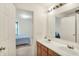 Bright bathroom featuring double sinks, a large mirror, and doorway to a bedroom with blue accents at 10828 Young Lake Dr, Indianapolis, IN 46229