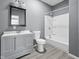 Modern bathroom features stylish gray vanity, toilet, mirror, and shower-tub combo with white tile at 1130 W Congress Ave, Indianapolis, IN 46208
