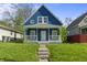 Charming blue two-story home featuring a cozy front porch and landscaped front yard on a sunny day at 1130 W Congress Ave, Indianapolis, IN 46208